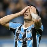 Meia Cristaldo, do Grêmio, lamentando com as mãos na cabeça em jogo na Arena, em 2024