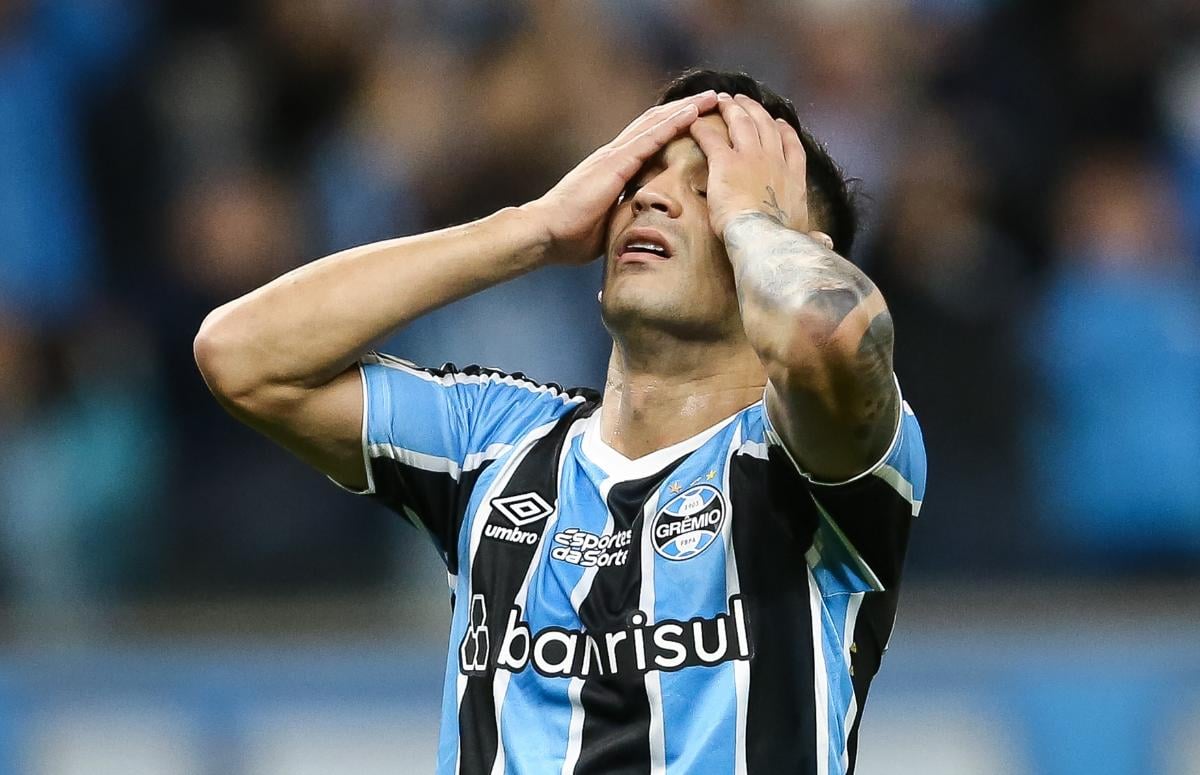 Meia Cristaldo, do Grêmio, lamentando com as mãos na cabeça em jogo na Arena, em 2024